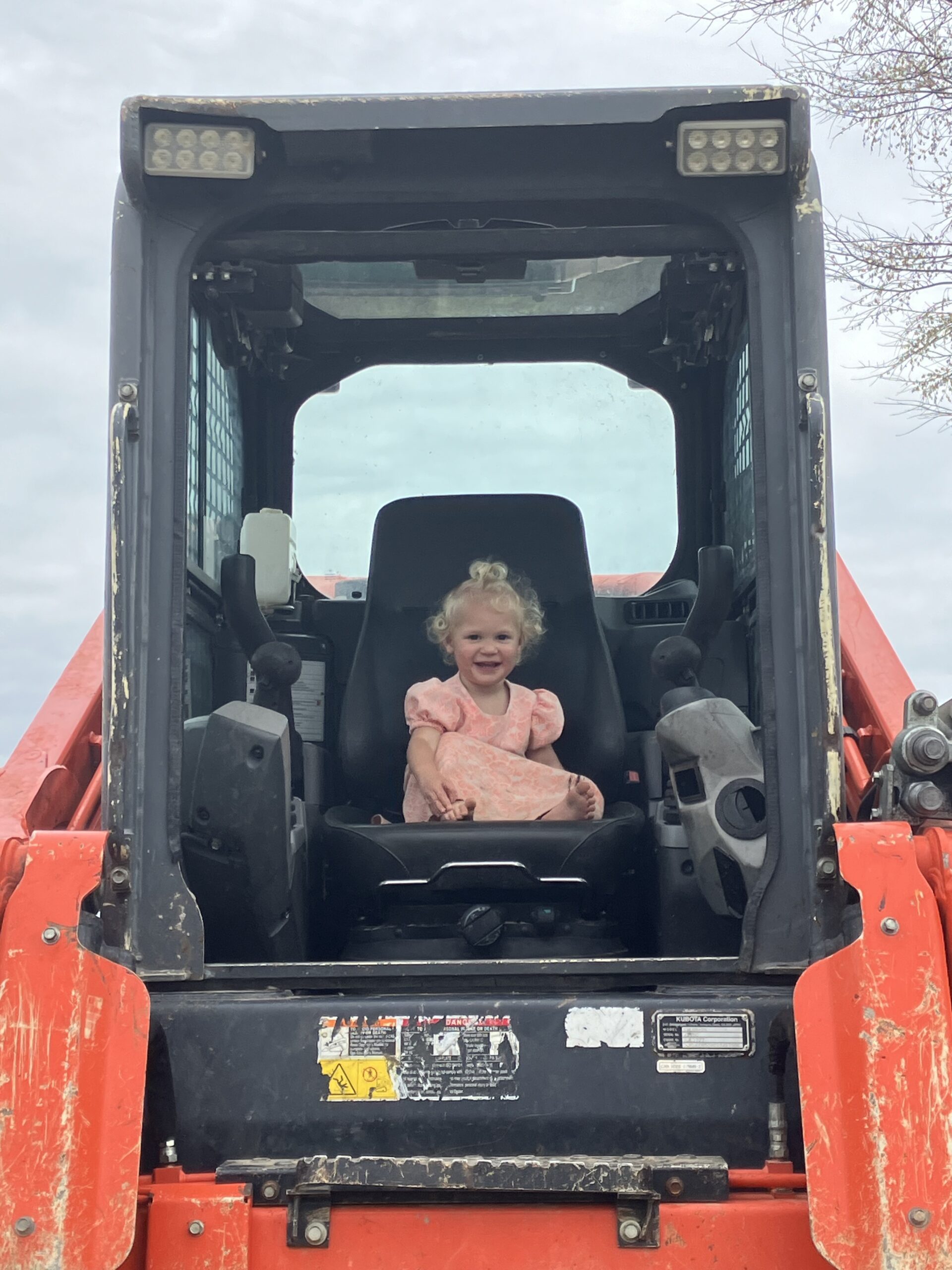 About Us 1 little girl sitting on backhoe machine